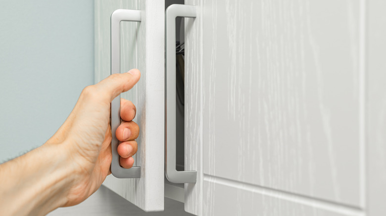 bir adamın eli dolabın kulpunu tutuyor