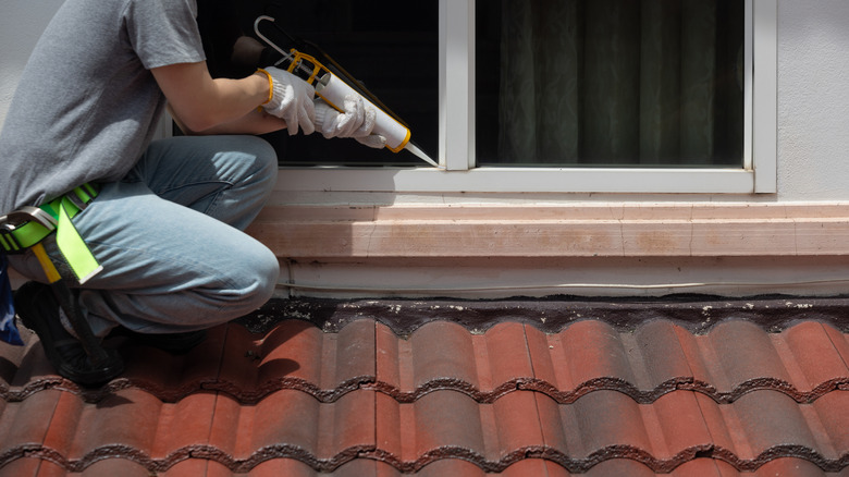 Pencere çerçevesi etrafına kalafat uygulayan kişi