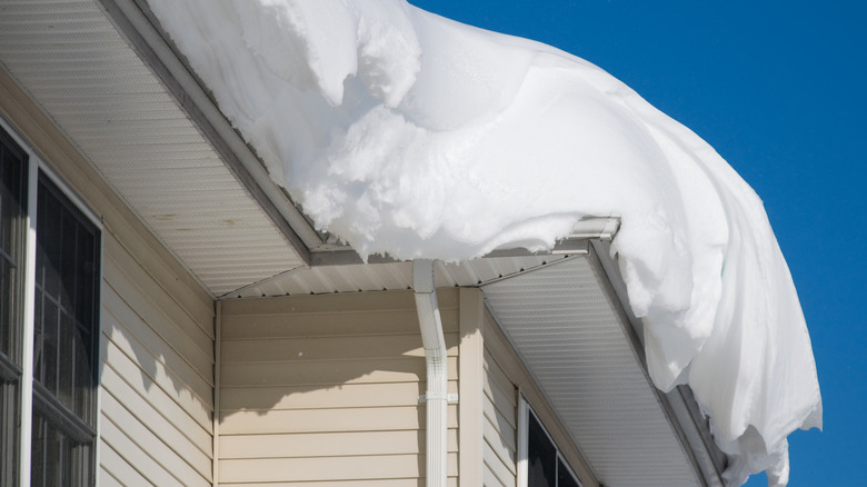 Bir evin çatısının kenarından sarkan yoğun kar