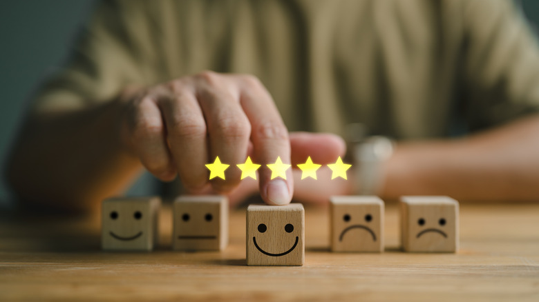 Mutlu ve üzgün yüzlerin sıralandığı beş blok ve üzerinde beş yıldız simgesi bulunan gülümseyen bloğu ileriye doğru iten bir el