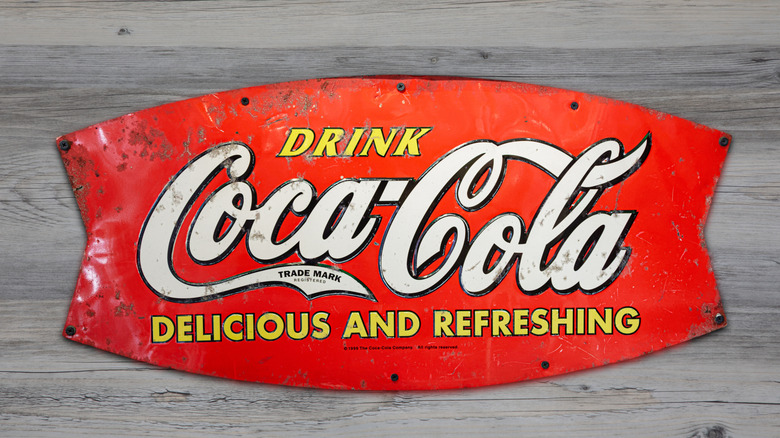 Ahşap bir duvara eski bir Coca Cola metal tabelası.
