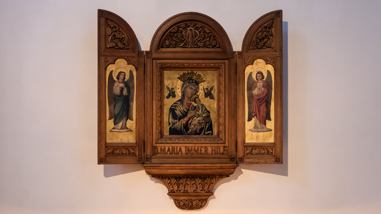 Duvarda açık bir şekilde asılı duran dini bir üç parça.