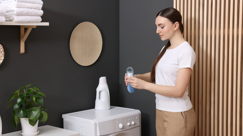 Çamaşır odasındaki şapkaya yumuşatıcı döken bir kadın