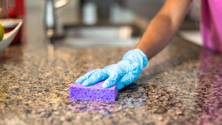 Bir kişi taş tezgahı süngerle temizler.
