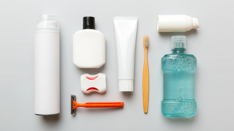 Turuncu bir ustura ve diş fırçası gibi kişisel bakım ürünleri beyaz bir yüzey üzerinde duruyor.