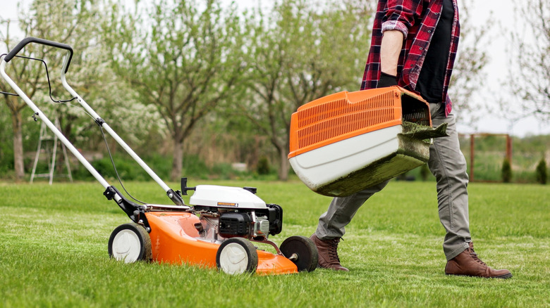 Turuncu çim biçme makinesi olan adam