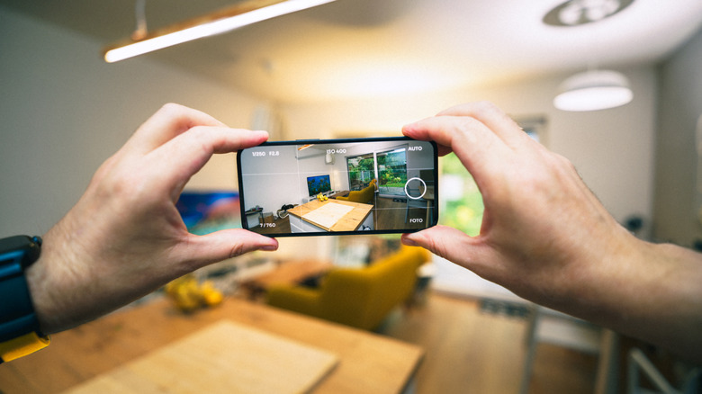 Daire satmak için fotoğraf çeken akıllı telefonu tutan eller.