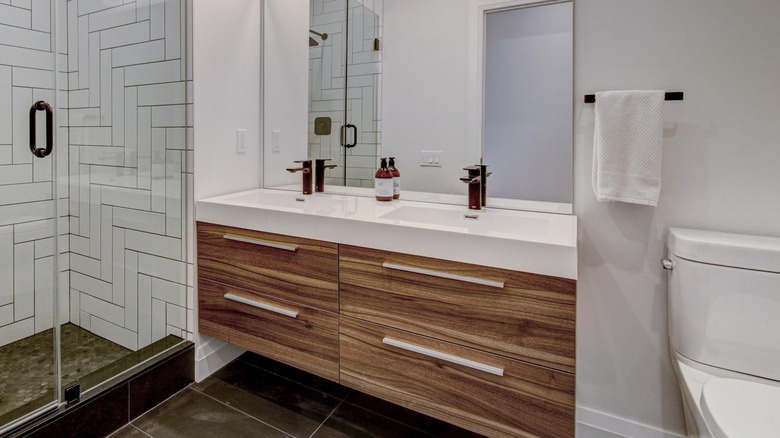 Şık çekmeceli ve büyük bir aynalı ahşap tuvalet masasına sahip çağdaş bir banyo