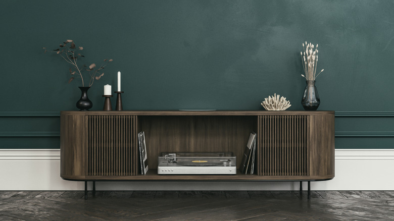 Yeşil bir duvara karşı koyu ahşap medya dolabı