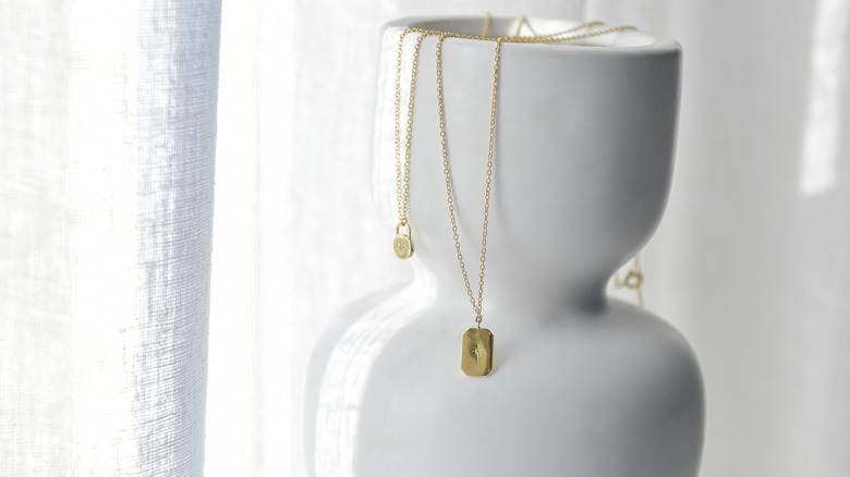 Üst kısmında kolyeler asılı olan beyaz bir vazonun yakın çekimi