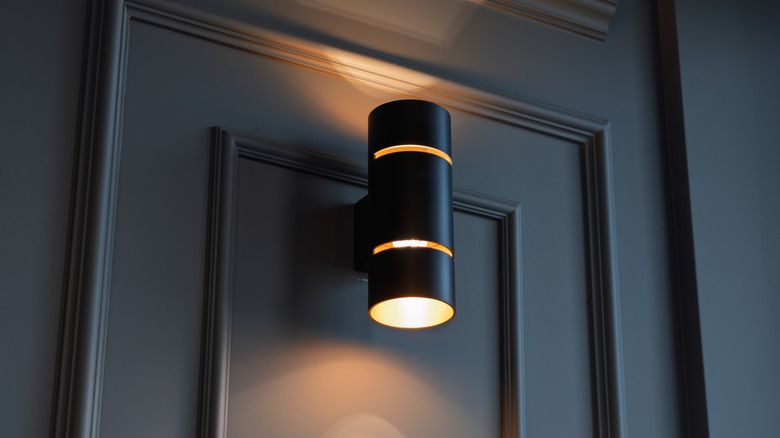 Panelli bir duvarı yumuşak bir şekilde aydınlatan siyah pille çalışan duvar lambasının yakın çekimi