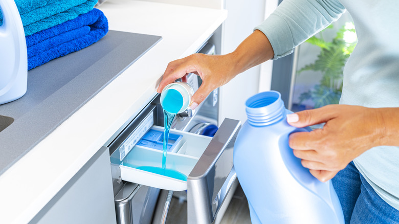 Kadın çamaşır makinesine deterjan döküyor