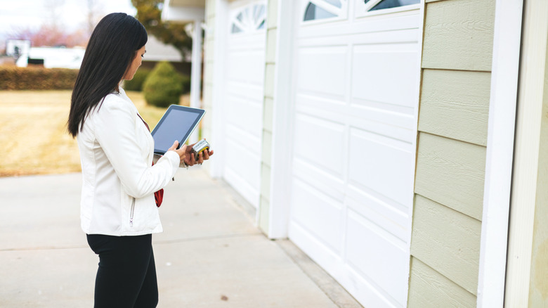 Garaj kapısını Wi-Fi aracılığıyla açmak için iPad'i uzaktan kumanda olarak kullanan kadın.
