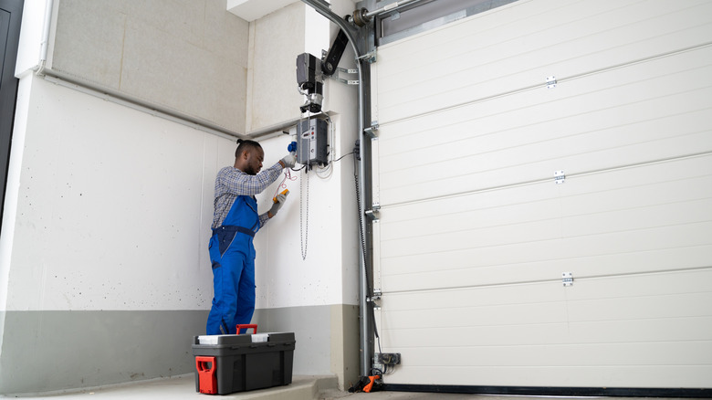Adam, garaj kapısına uzaktan kumanda eklemek için kablosuz garaj açma alıcısı takıyor.