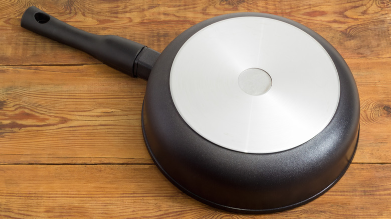 ahşap bir yüzey üzerinde ters çevrilmiş pürüzsüz çelik tabanlı tava