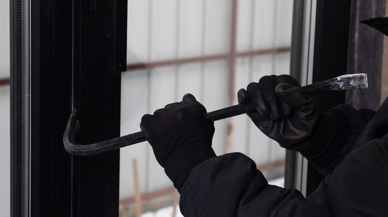 Bir evin penceresini açmak için levye kullanan eller.