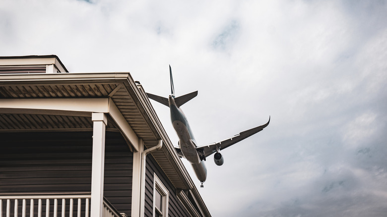 Uçak çok alçaktan uçuyor, bir evin çatısına yakın.