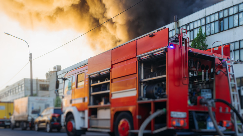 Bir apartmanın dışına konuşlanmış bir itfaiye aracı dumanla dolup taşıyor.
