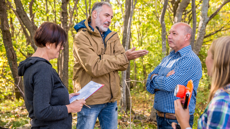Kadastrocu ve arazi sahipleri ormanlık bir alanda mülk sınırları konusunda kavga ediyor.