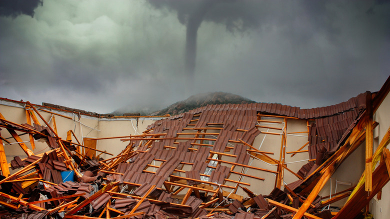 Arkasında bir kasırga olan yıkılmış bir ev.