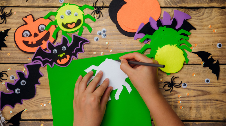 Cadılar Bayramı şablonunun etrafında çizim yapan bir el