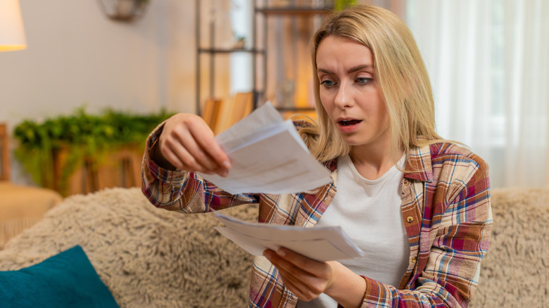 Bir kadın yüzünde şaşkın bir ifadeyle banknota bakıyor.