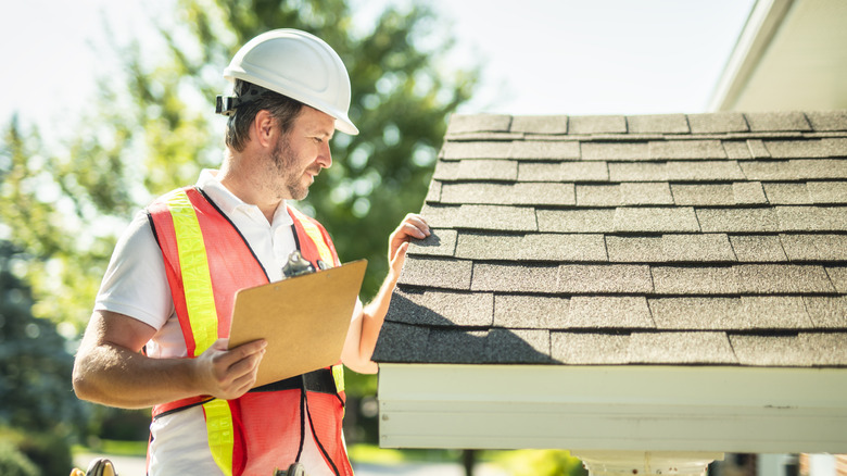 Bir erkek araştırmacı çatıdaki kiremitleri inceliyor.