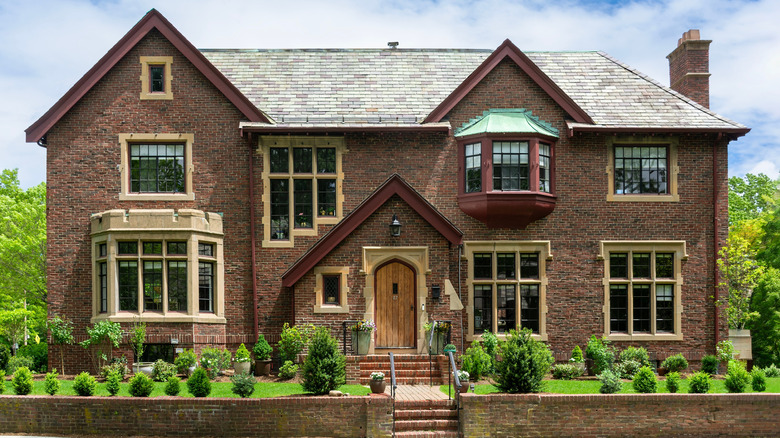 Önünde kısa, bakımlı çitlerin olduğu Tudor tarzı ev