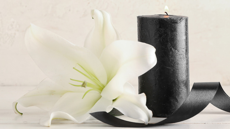 Siyah bir mum ve beyaz çiçekli kurdele