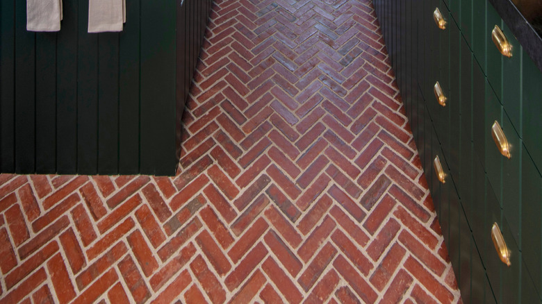 Mutfak tasarımında yeşil dolaplı tuğla balıksırtı zemin