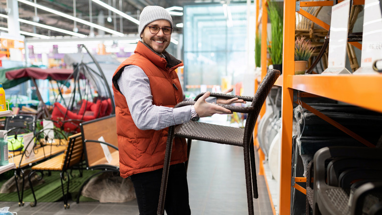 Bere ve yelek giyen adam veranda mobilyası satın alıyor