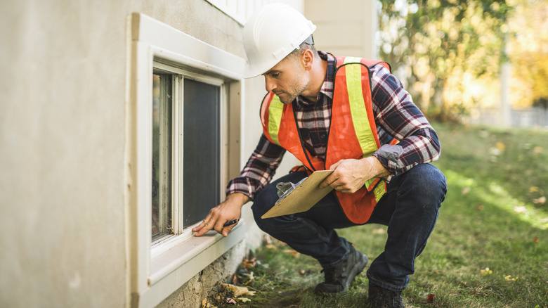 Bir ev müfettişi dış mekan penceresini incelerken elinde bir pano tutuyor