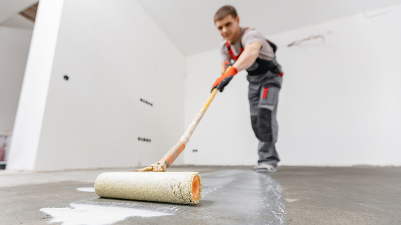 Beton zemini astarlamak için silindir kullanan profesyonel işçi