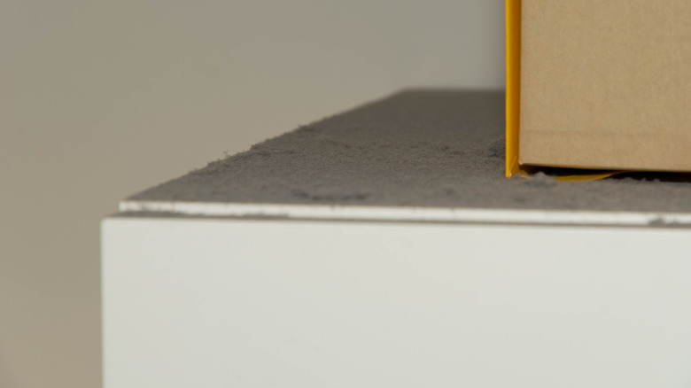 Uzun, müstakil bir dolabın üstü tozla kaplı.