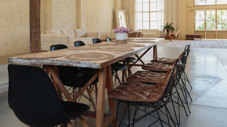 Tel ayaklı kahverengi deri Eames sandalyeler de dahil olmak üzere etrafını saran sandalyelerle dolu bir yemek masası