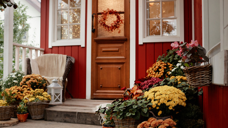 Annelerle dolu sepetler ve hasır sandalyenin olduğu kırmızı bir evin ön verandası.