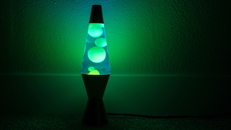 Karanlık bir odayı aydınlatan mavi-yeşil bir lav lambası.