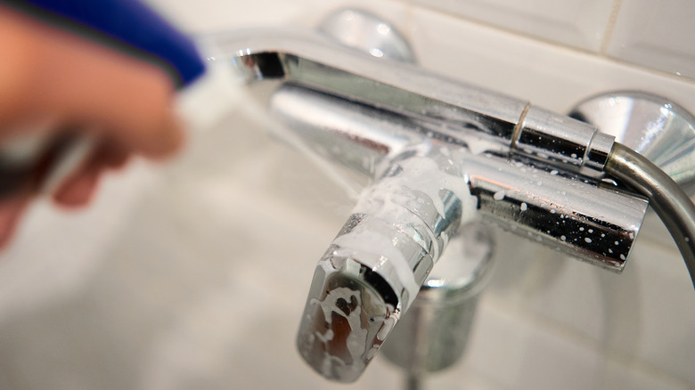 Krom banyo musluğuna temizleyici püskürtmek