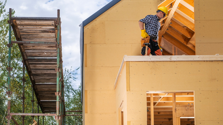 inşaat halindeki evin çatısında duran müteahhit