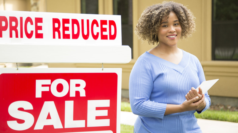 İndirimli fiyat tabelasının yanında duran kadın