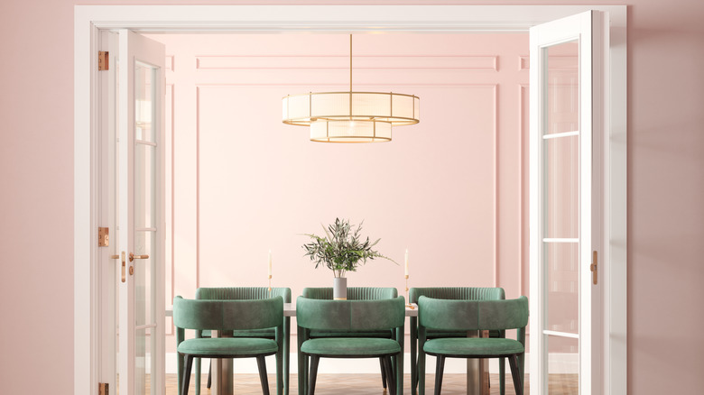 Yumuşak pembe yemek odasındaki masanın üzerinde bir avize asılı duruyor