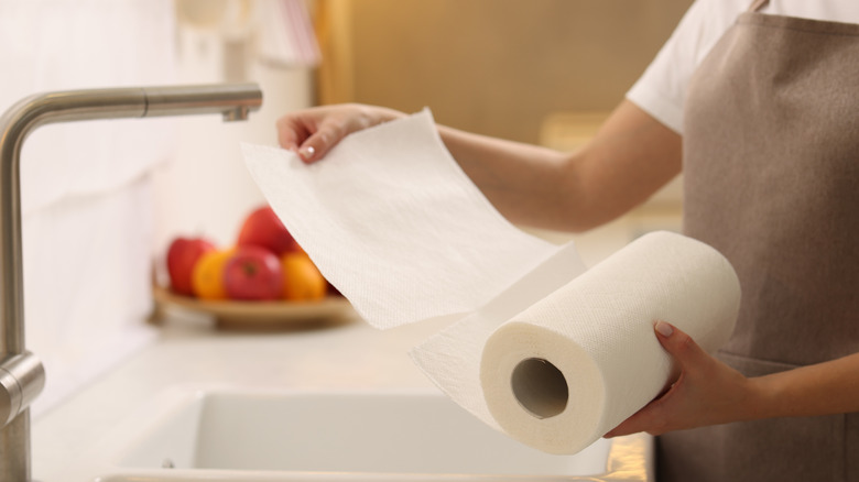 Mutfak lavabosunun önünde duran biri tarafından kağıt havlu rulosunun çarşafları yırtılıyor