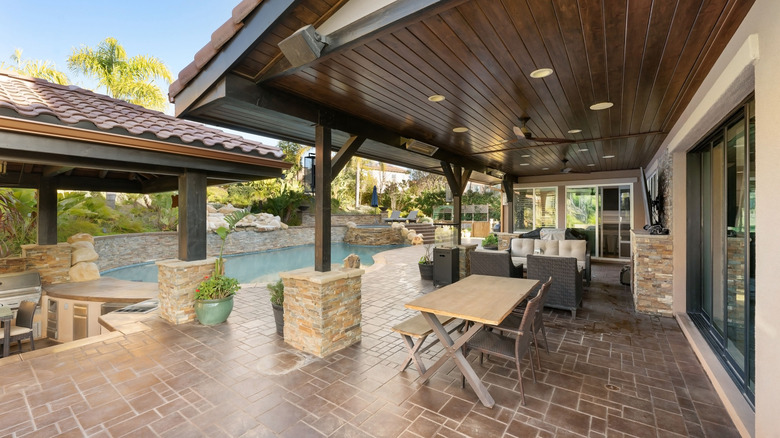 Kapalı verandası, havuzu, yemyeşil peyzajı ve taş detaylarıyla lüks bir açık hava yaşam alanı.