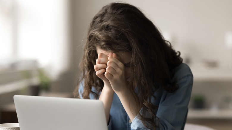 Genç bir kadın bilgisayarda çalışırken dua ediyor