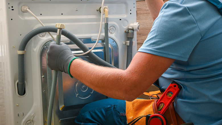 Çamaşır makinesinin tahliye hortumunu tamir eden tamirci