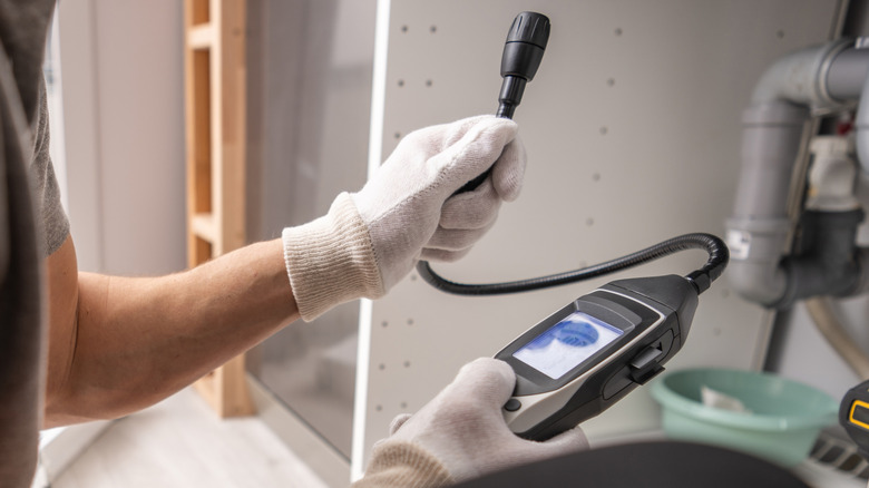 Gaz sızıntısı dedektörünü tutan bir adam