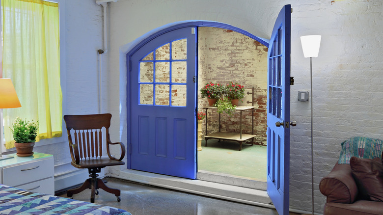 Çarpıcı mavi renkte boyanmış, yarı açık Fransız kapılı şık yatak odası