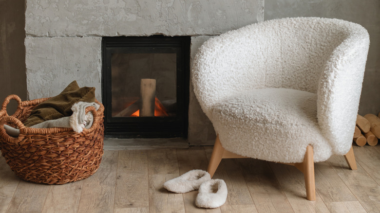 Şöminenin yanındaki beyaz yün sandalye