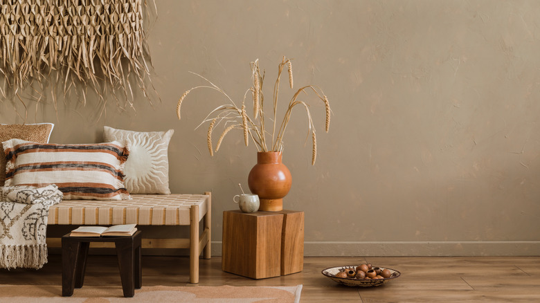 Çim unsurlar ve battaniye ile yastıklar içeren dokuma bir bank içeren oda dekoru.