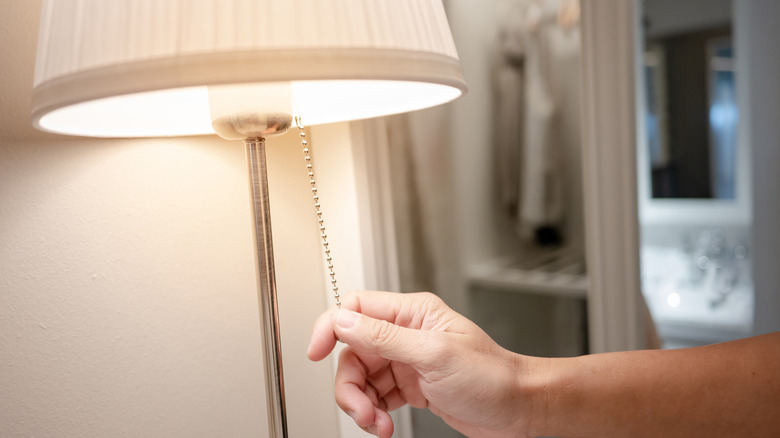 Bir el bir kabloyla lambayı kapatıyor.